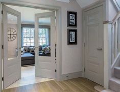 an open door leading to a living room with stairs and pictures hanging on the wall