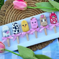 an assortment of farm animals on skewers next to tulips