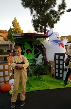 a young boy standing in front of a car decorated for halloween with ghost and pumpkins