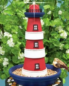 a red and white lighthouse sitting on top of a bird feeder