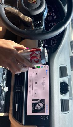 a person is holding a drink in their hand while sitting at the wheel of a car