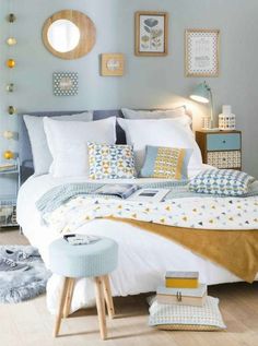 a bedroom with blue walls and white bedding, yellow accents on the headboard