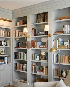 a living room filled with lots of books on top of book shelves next to a couch