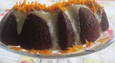 a cake with frosting and orange zest on top sitting in a glass dish