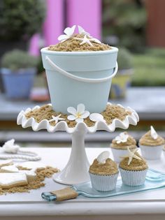 cupcakes with white frosting and flowers are on a cake stand next to other cupcakes