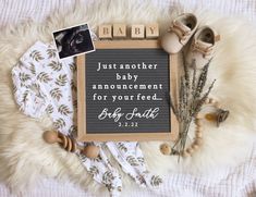 a baby announcement with shoes and other items on top of a blanket next to it