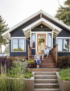 two people are sitting on the steps in front of a house that is painted blue