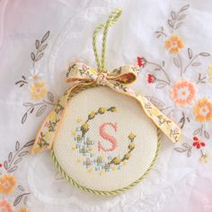 a cross stitch ornament hanging from a doily on a white tablecloth