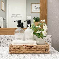 a bathroom counter with soap, lotion and flowers in a wicker basket on it