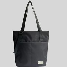 a black tote bag sitting on top of a white table next to a gray wall