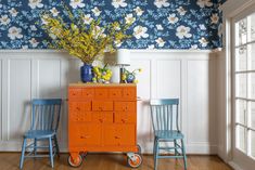 an orange dresser and two blue chairs in a room