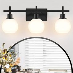 three lights are on the wall above a mirror