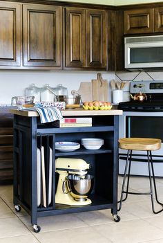 a kitchen island with a mixer on it in front of a stove and microwave oven