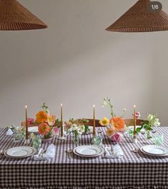 the table is set with plates and flowers on it, along with two hanging lamps