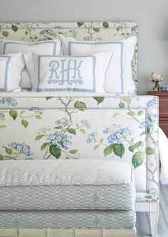 a bed with blue and white flowers on the headboard, pillows and pillow cases