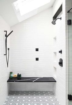 a black and white tiled bathroom with skylight