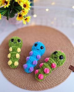 three small crocheted animals sitting on top of a brown plate next to yellow flowers