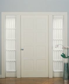 a vase with flowers sitting in front of two white doors that lead to another room