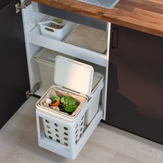 an open refrigerator with food in it on the floor next to a sink and counter