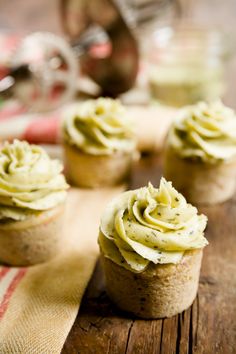 cupcakes with green frosting sitting on a wooden table