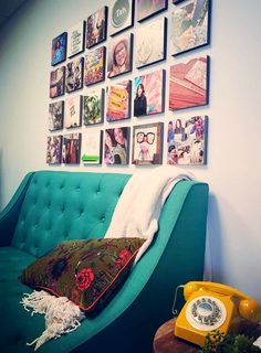 a blue couch sitting in front of a wall with pictures on it and a phone