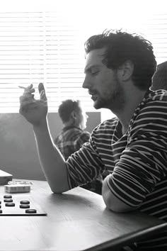 a man sitting at a table with his hand up in the air while playing an electronic game