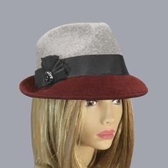 This beautiful ladies fedora is made from  fur felt, and hand draped over an antique hat block. Hand finished with authentic millinery techniques. Created with two colors of felt, and embellished with grosgrain and twill ribbons.   Please indicate your head size measurement when ordering (measure your head horizontally just above your eyebrows). When you receive your hat, there will be a small ribbon inside to fine-tune the fit, and a hat box for safe storage. Note: Colors will vary depending on your monitor and there will also be some variations due to dye lots. I personally create each hat one at a time, and no two are ever exactly the same.  My hats are 100% handmade for you, using traditional Millinery techniques and the highest quality fabrics and details.  I frequently trim  my hats Elegant Gray Felt Hat With Short Brim, Elegant Gray Brimmed Felt Hat, Elegant Gray Wide Brim Felt Hat, Elegant Gray Fedora For Winter, Elegant Gray Felt Hat With Curved Brim, Elegant Burgundy Hat For Winter, Trilby Fedora, Antique Hat, Hat Blocks