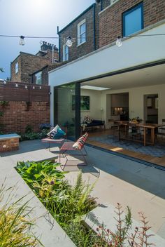 an outdoor patio with chairs and tables next to a brick wall that has glass doors on it