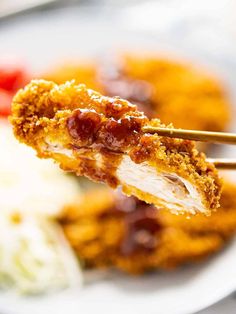 a close up of food on a plate with chopsticks in the foreground