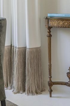 a wooden table with two tassels on top of it next to a white curtain