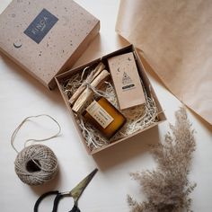 an open box with some items in it next to scissors and twine on the table