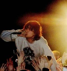 a man standing on top of a stage with his hands in the air while holding a microphone