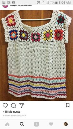 a crocheted top hanging on a wooden wall