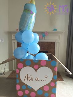 it's a baby shower in a box with balloons and a bottle on top