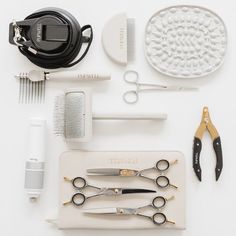 scissors, combs, and other items laid out on a white surface with hair clippers