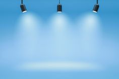 three black lamps on a blue background with spot lights in the middle and one light at the end