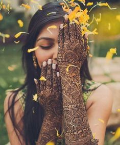 a woman holding her hands up to her face with yellow flowers all over her body