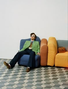 a man sitting on top of a blue couch in front of a white wall and floor