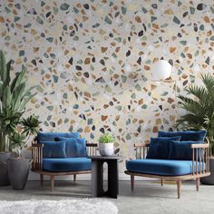 two chairs and a table in front of a wall with plants