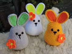 three crocheted easter bunnies sitting on top of a pile of white fur