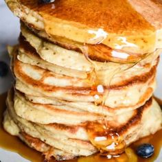 a stack of pancakes covered in syrup and blueberries