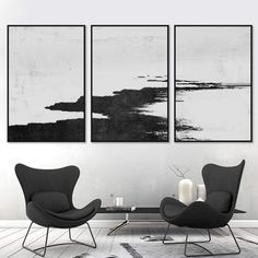 two black and white paintings hanging on the wall in a living room with modern furniture