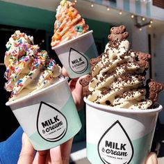 three ice creams with sprinkles and cookies in them are being held up