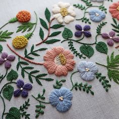 an embroidered piece with flowers and leaves on it