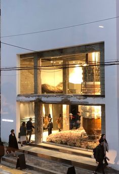 people walking in front of a building that is lit up at night with lights on