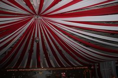 a large red and white striped tent with lights on it's ceiling is shown