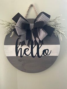 a wooden sign that says hello with a bow hanging on the front of it,