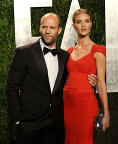 a man and woman standing next to each other in front of a wall with letters on it