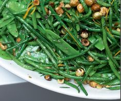 green beans and other vegetables on a white plate with some seasoning sprinkles