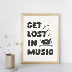 a framed poster with the words get lost in music on it next to a plant